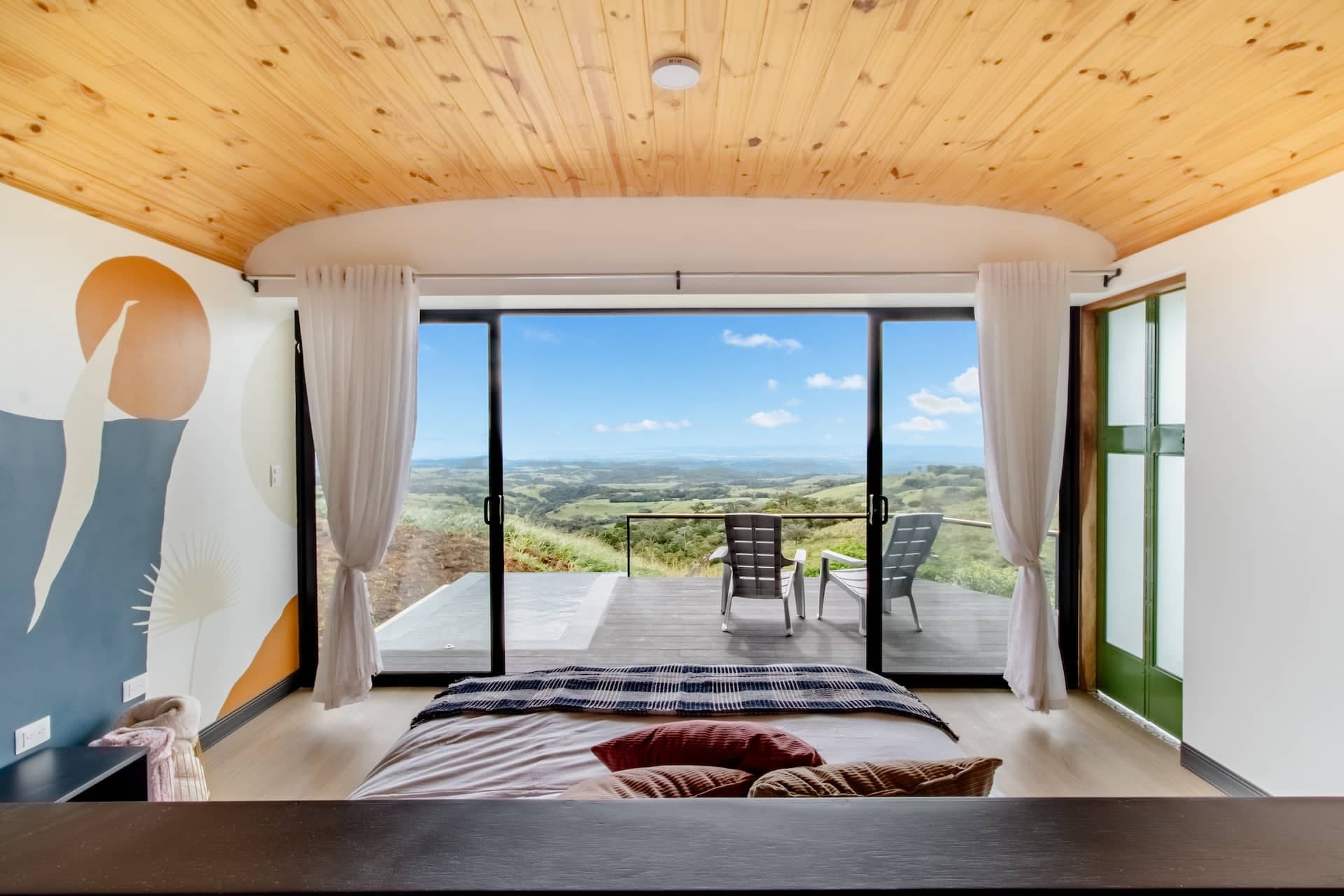 Bed facing floor-to-ceiling glass and the valley
