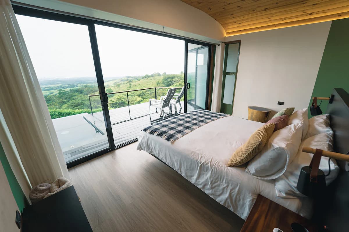 Bedroom with a glass wall and valley view
